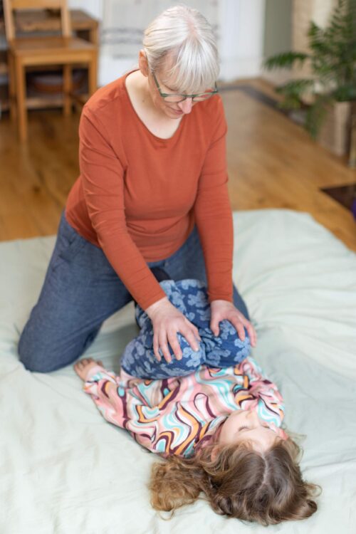 Shiatsu massage practitioner in Govanhill, Glasgow working with child on hip rotations for supporting stiff hip joints and psoas muscle.